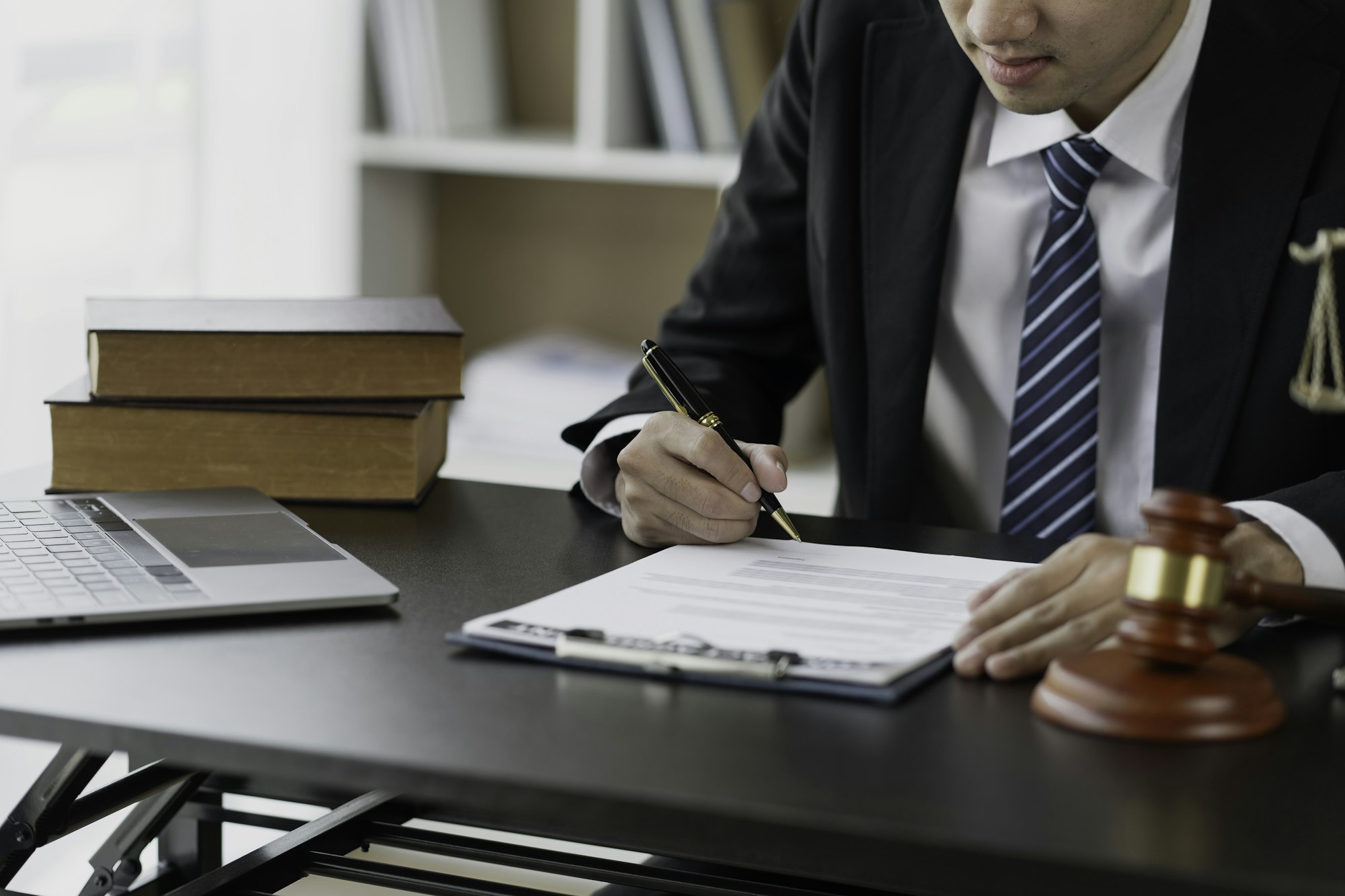 A lawyer working at a desk with legal documents, books, a laptop