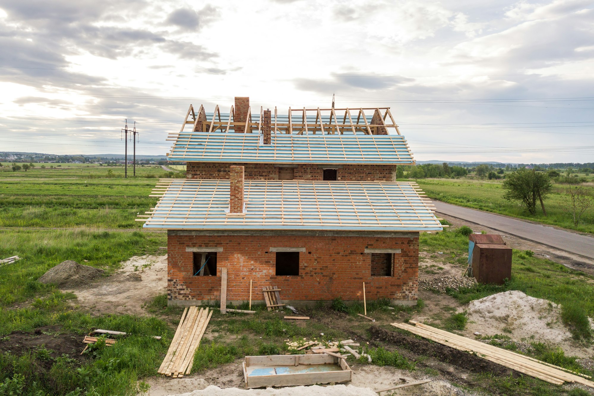 Aerial view of a brick house with wooden roof frame under construction